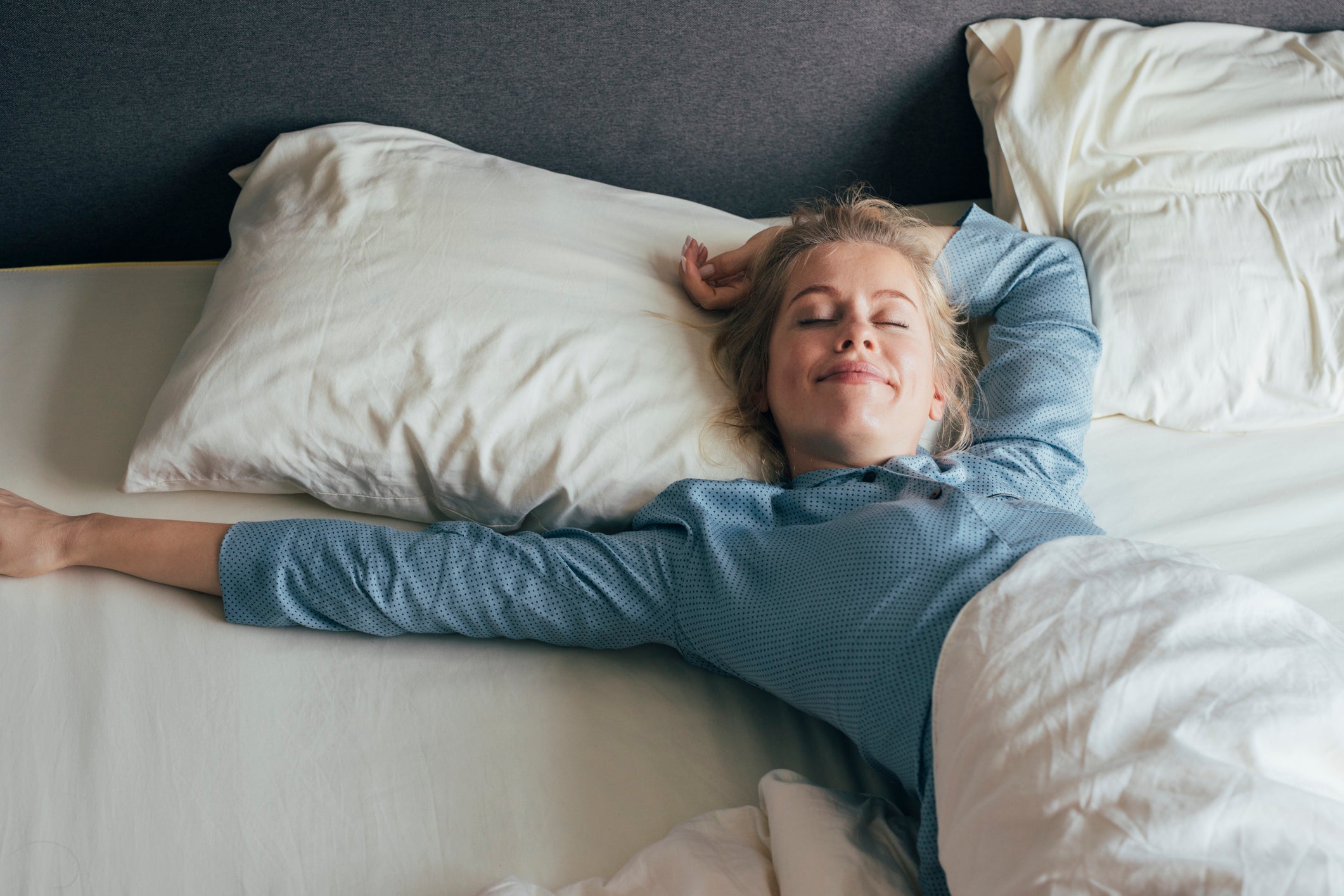 Woman lying on a bed with white pillows and bedding