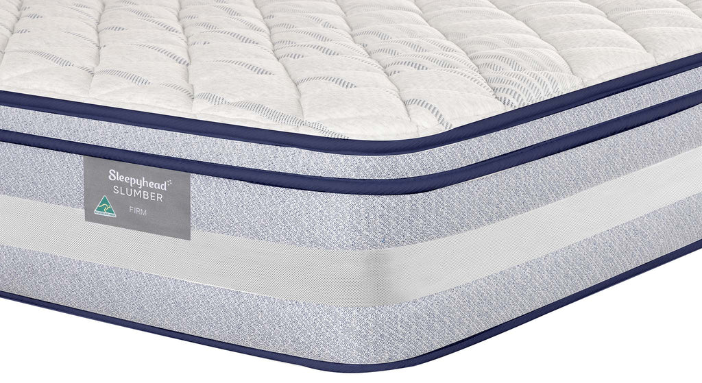 A close-up studio shot of a Sleepyhead mattress corner showing a quilted white top, a textured light gray side, and navy blue piping. A Sleepyhead Slumber label is visible on the side.