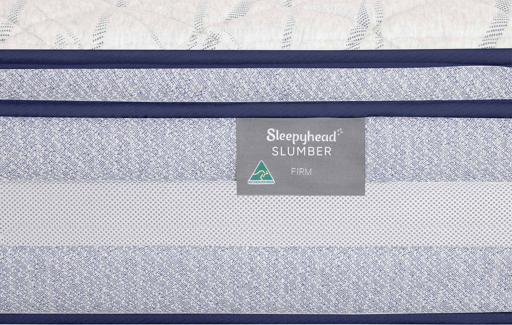 Close-up of a mattress side panel showing the Sleepyhead Slumber Firm label, with blue trim and a textured white mattress top visible.