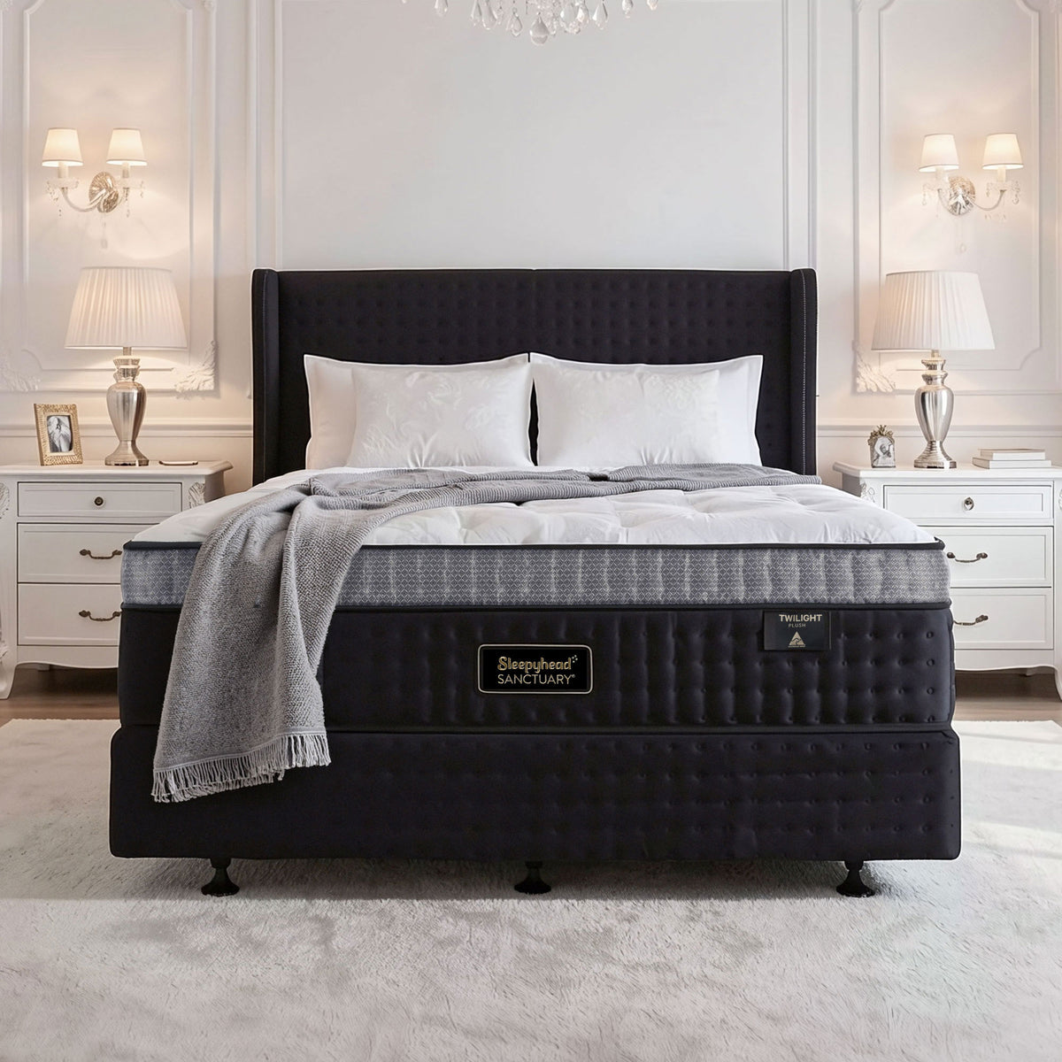 A luxury bed setup featuring a Sleepyhead mattress with a gray patterned side panel and white bedding, styled in a classic, symmetrical bedroom with white nightstands, lamps, and a white paneled wall.